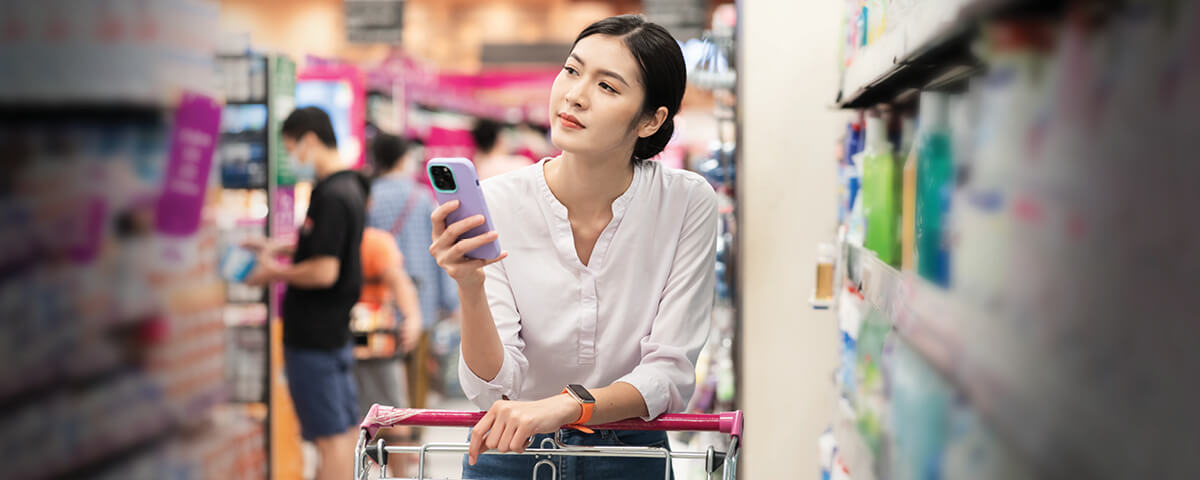 Photo of a woman at the grocery store with her mobile phone. Custom Media recently delivered a webinar about Japanese consumer behavior. 